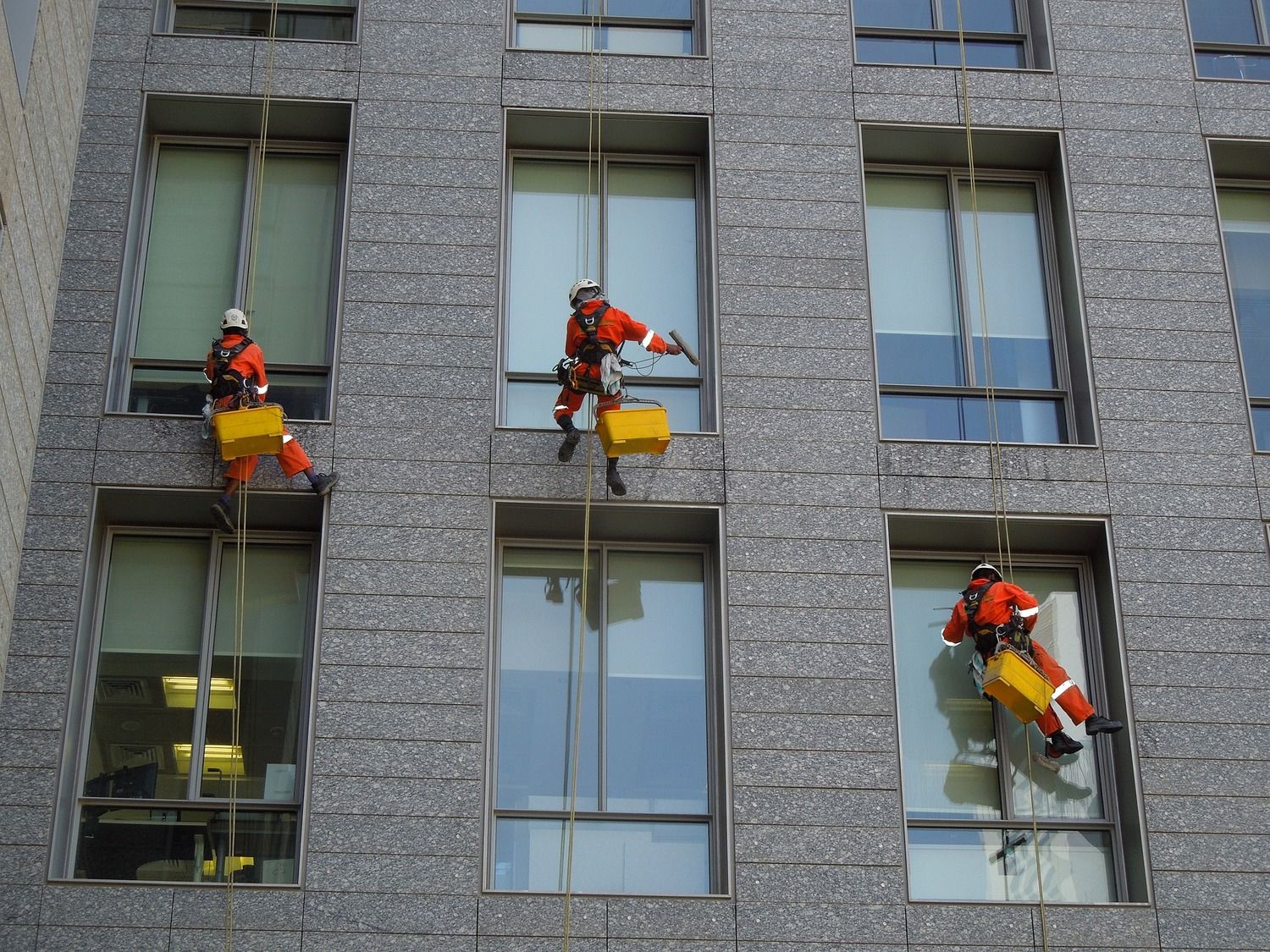 Rope access technicians cleaning the windows of a high rise building.